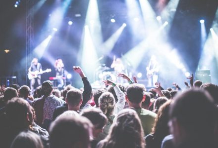 Energetic concert scene with a vibrant audience and band performing under bright lights.